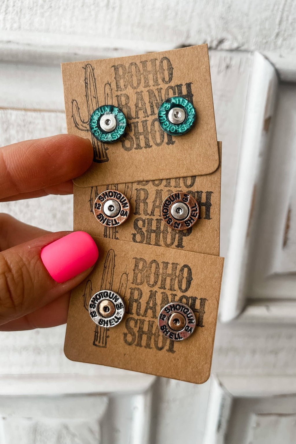 Pair of earrings on a 'Boho Ranch Shop' card held by a hand with pink nail polish.