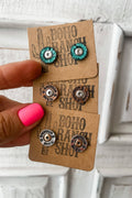 Pair of earrings on a 'Boho Ranch Shop' card held by a hand with pink nail polish.