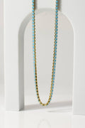 Necklace with blue beads on a white stand against a light gray background