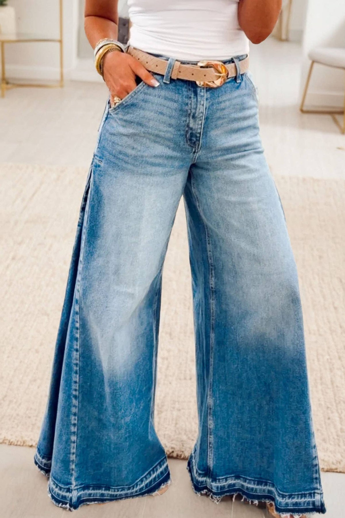 Person wearing blue wide-leg jeans with a white top and gold belt.