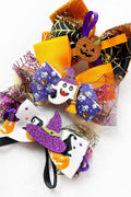 Two Halloween-themed hair bows on a white background. One bow is orange, black, and purple with spiderweb and jack-o'-lantern details.