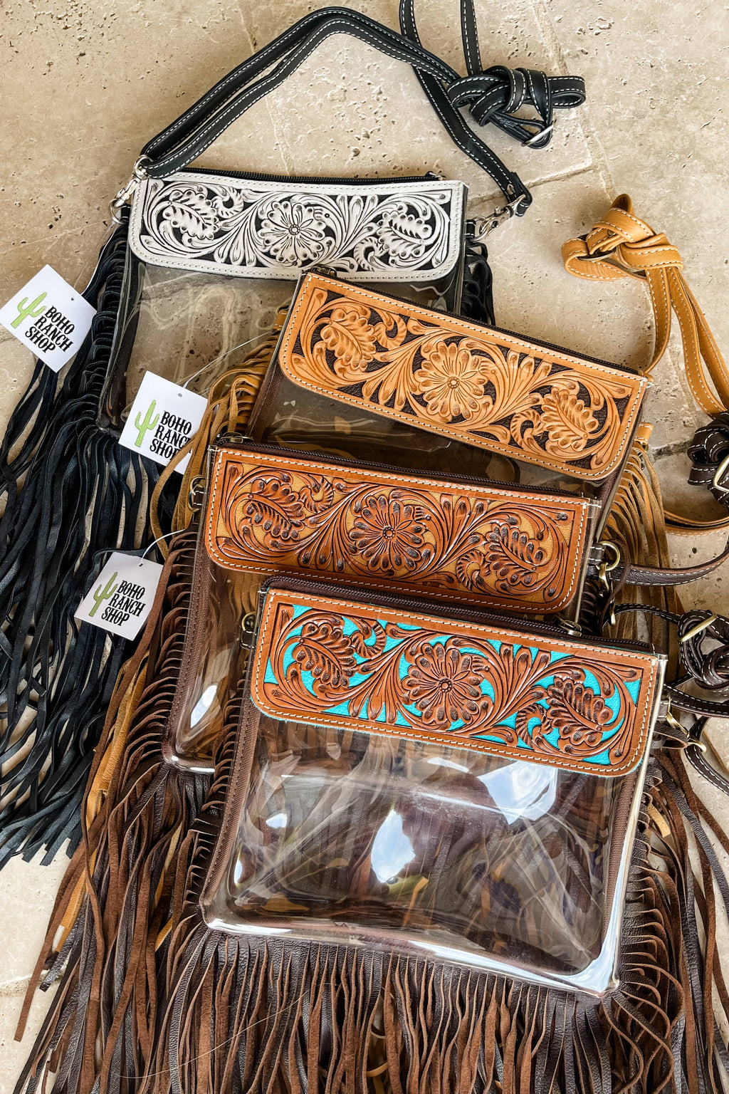 Leather bags with intricate designs and fringes on a beige surface