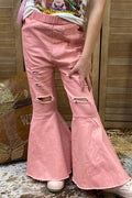 A person wearing dusty pink flared jeans with distressed rips on the legs, paired with a graphic t-shirt and white sneakers, standing in front of a wooden slat wall.