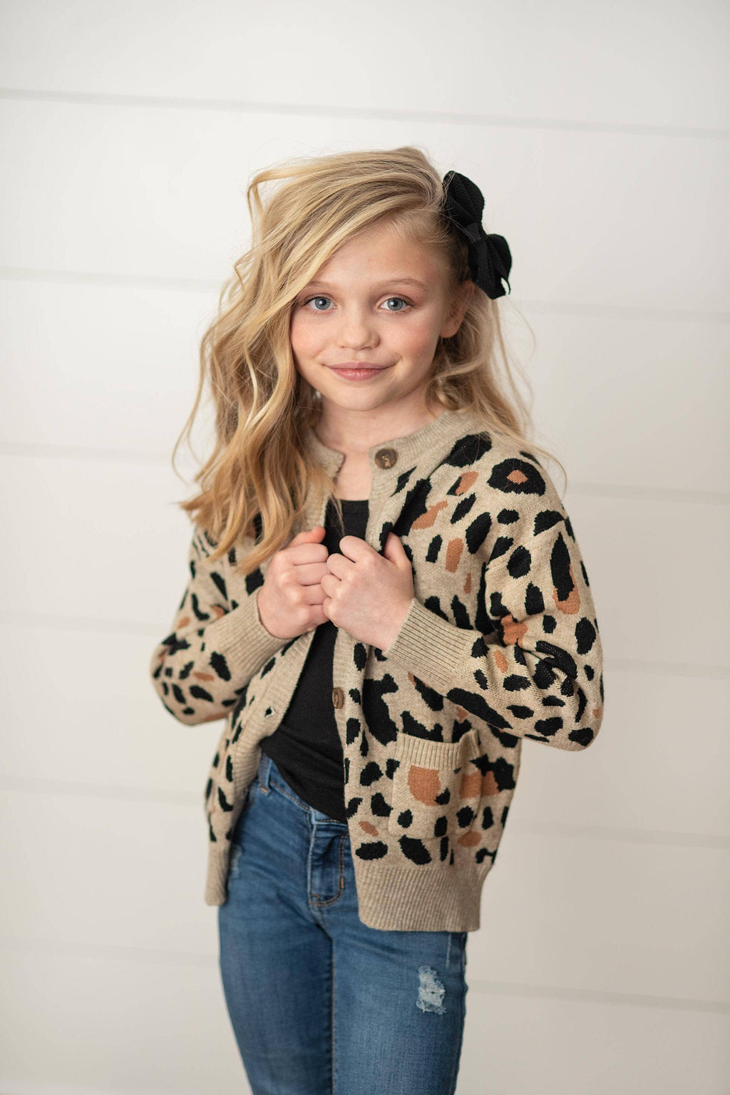 Young girl wearing a leopard print cardigan against a white background